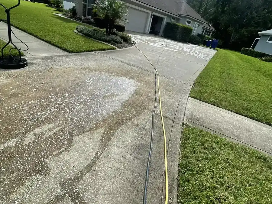 Concrete driveway mid-clean, with the cleaned half meeting the untouched half