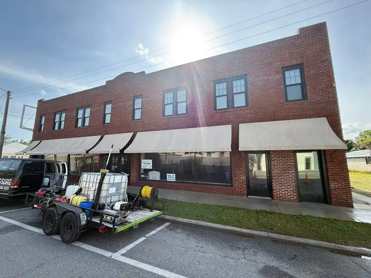 Brick retail row with tenant awnings during a commercial facade cleaning