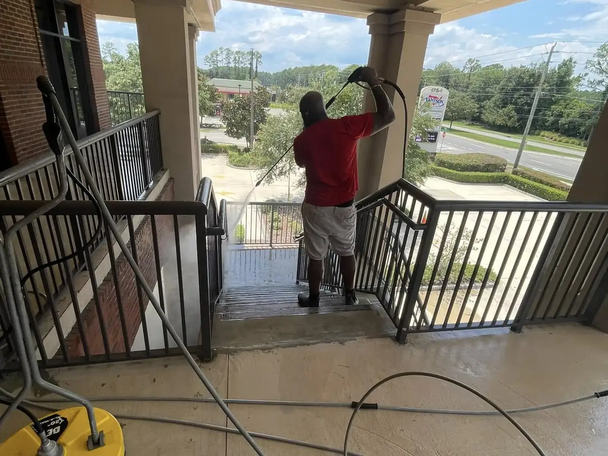 Technician cleaning a covered common area walkway at a multi-family property