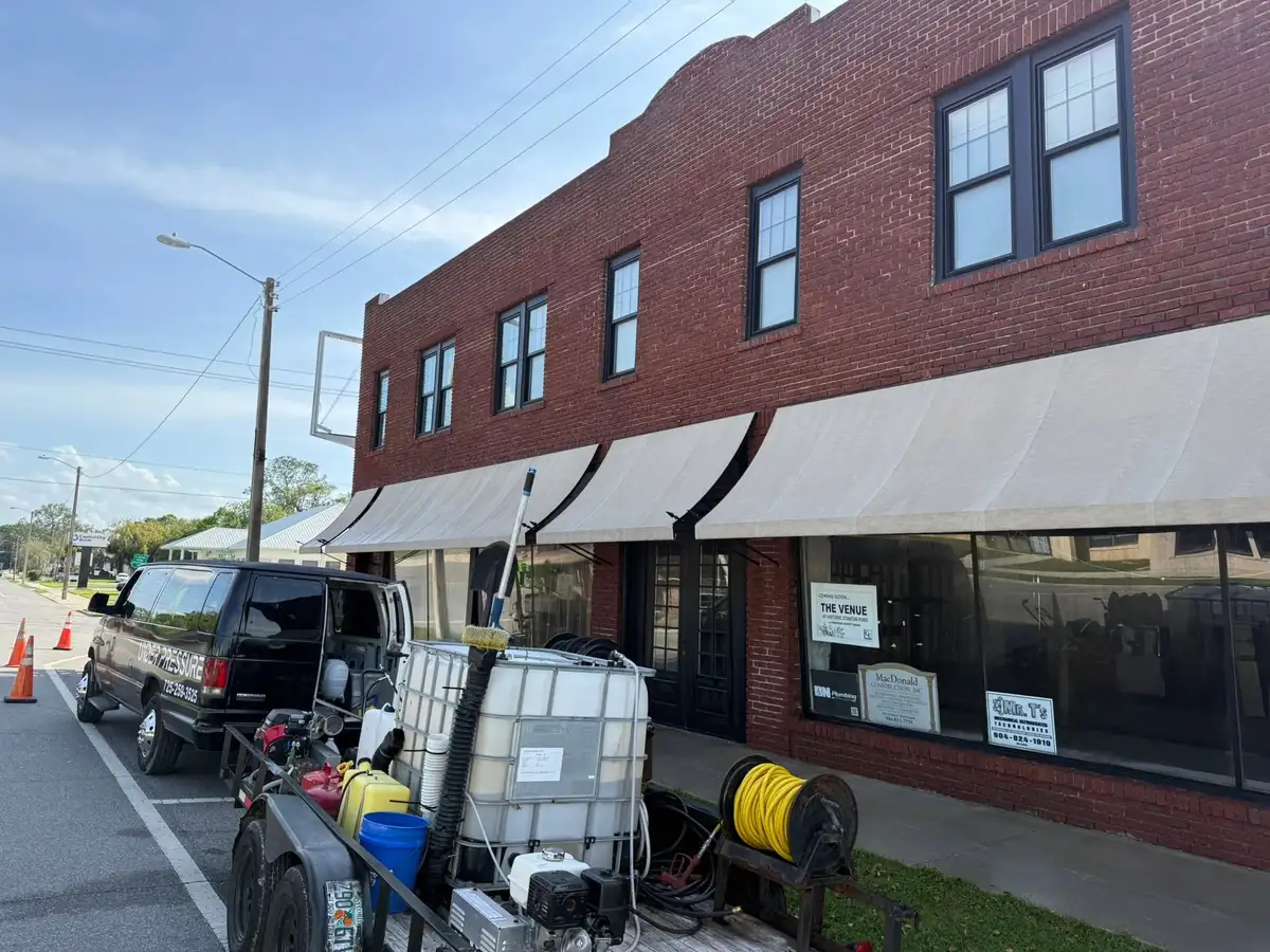 Brick retail building with tenant awnings during a commercial exterior cleaning